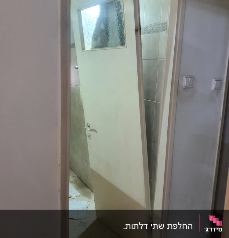 דלת עץ עם חלון זכוכית שבורה בחדר אמבטיה